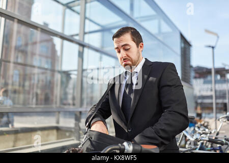 Unternehmer als ein pendler Für die Fahrrad Schlüssel frustriert aussieht Stockfoto