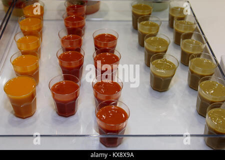 Grüne Erbse, Orange Karotte und rote Tomaten konzentrieren Saucen in kleinen Plastikbecher Stockfoto