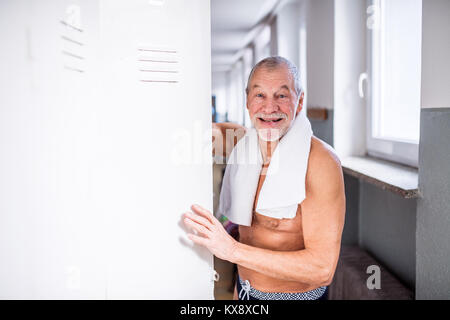Älterer Mann durch die Schließfächer in ein Hallenbad. Stockfoto
