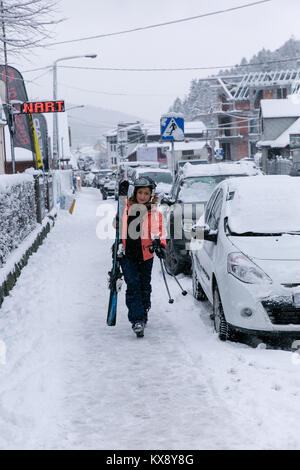 Frau mit Skiern in vollem Gang Wandern Skifahren in Ski Stiefel im Schnee durch die Straßen von Szczyrk Polen Stockfoto