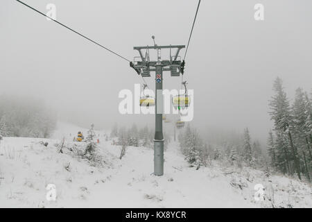 Ski Sessellift bringt Skifahrer und Snowboarder auf den Berg Skrzyczne nach starker Schneefall auf einem nebligen Wintertag in Szczyrk ski resort in Polen Stockfoto