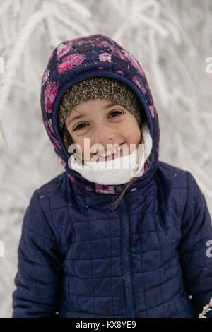 Junge 7 Jahre alt Happy girl Lächeln und Lachen bis in die warme Kleidung im Winter Schnee Landschaft kuschelten Stockfoto