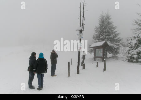 Touristen fragen im Schnee Blick auf die Wanderkarte an einem nebligen Gipfel Der Berg Skrzyczne in Szczyrk, Süden Polens in der Woiwodschaft Schlesien Stockfoto