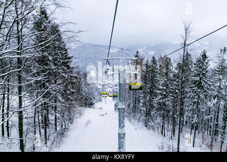 Ski Sessellift bringt Skifahrer und Snowboarder auf den Berg Skrzyczne nach starker Schneefall auf einem nebligen Wintertag in Szczyrk ski resort in Polen Stockfoto