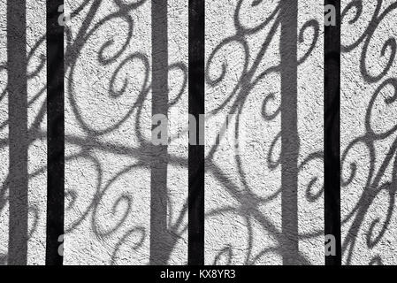 Abstrakte Schatten einer gekrümmten schmiedeeiserne Tür an einer Wand, die Schwarz-Weiß-Fotografie Stockfoto