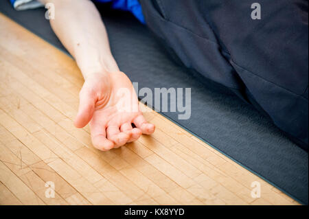 Man Yoga im Innenraum in einem Retreat Raum tun Leiche Pose-Savasana - Nahaufnahme einer Hand Stockfoto