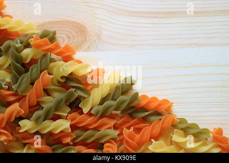 Blick von oben auf die Ungekocht drei Farben spiralförmige Pasta auf Holztisch, Bild horizontal mit Freiraum für Text oder Design Stockfoto