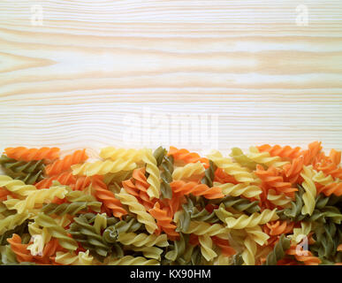 Ungekocht drei Farben Fusilli auf dem hölzernen Tisch, horizontale Ansicht von oben Foto mit Freiraum für Text oder Design Stockfoto