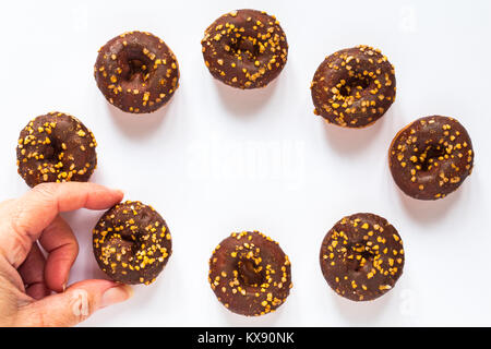 Acht 8 Tesco festliche Mini Donuts in einem Ring mit Hand packte ein Satz auf Weiß Stockfoto