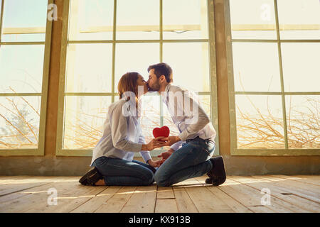 Ein liebevolles Paar mit einem roten Herzen küssen. Stockfoto