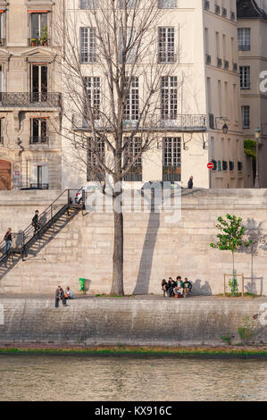 Paris Seine quai, Blick auf junge Menschen entspannend entlang des Quai d'Orleans auf der Ile St. Louis im Zentrum von Paris, Frankreich. Stockfoto