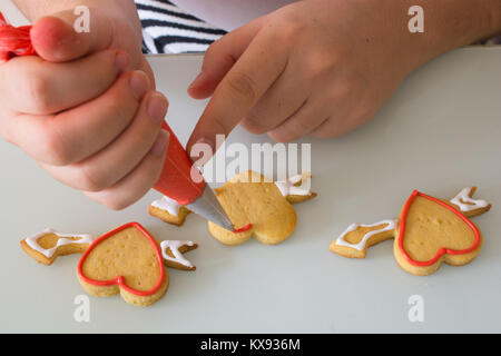 Frauen in der Küche bereiten für den Valentinstag. Frau Valentinstag cookie bereitet. schmückt Herzen formt mit seinen Händen. Ornamentik und sha Stockfoto