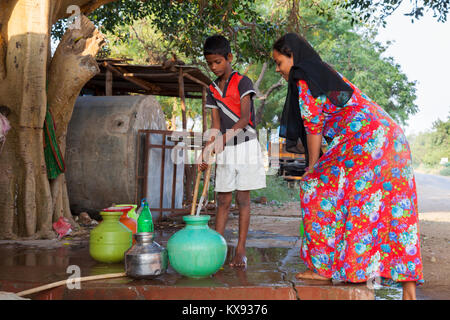 Indien, Karnataka,, Badami, indischer Junge ist Wasser beim Füllen Töpfe aus einer öffentlichen Wasserleitung Stockfoto