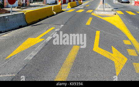 Gelbe temporäre Fahrbahnmarkierungen an einer Kreuzung in der Nähe einer Baustelle. Stockfoto