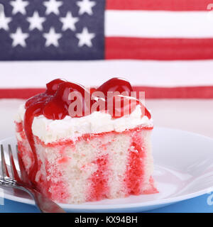 Stück Kuchen mit Kirschen auf einem Teller mit der amerikanischen Flagge im Hintergrund Stockfoto