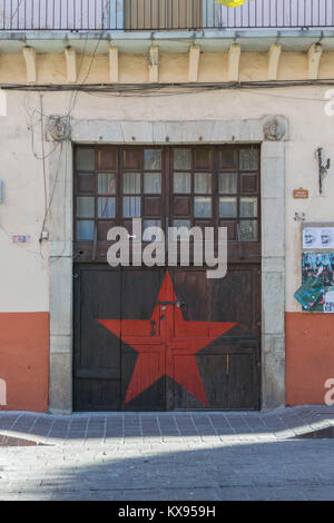 Store Front mit großen hölzernen Türen und einem großen roten Stern zwischen den beiden Türen, andere architektonische Details und Stein pflaster gemalt, Guanajuato Stockfoto