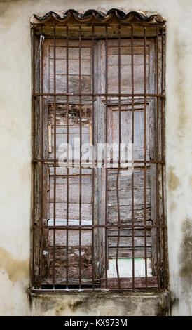 Alte unbemalten weißen Fensterläden im Fenster hinter rostigem Eisen bars auf unlackierte weiße Wand in Trinidad, Kuba Stockfoto