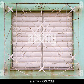 Weißen Fensterläden geschlossen am Fenster hinter White Metal Grill auf blass blaue Wand in Trinidad, Kuba Stockfoto