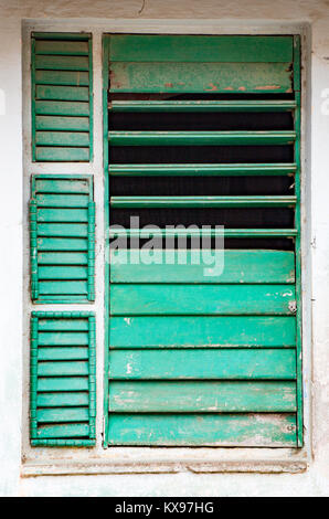 Teilweise offen angebrochen grünen Fensterläden in Fenster auf weiße Wand in Trinidad, Kuba Stockfoto