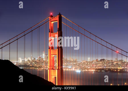 Golden Gate Bridge Close-up mit San Francisco Skyline Hintergrund auf einer klaren Winternacht. Stockfoto