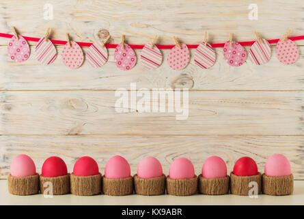 Ostereier und Ostern Dekor Papier Eiern mit einer rosa Schleife auf einem hölzernen Hintergrund. Selektiven Fokus. Stockfoto