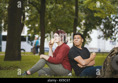 Paar jugendliche Touristen mit Rucksäcken Eis essen und Erholung in der City Park Stockfoto