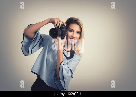 Fröhliche junge Frau, Foto vor der Kamera über grauen Hintergrund Stockfoto