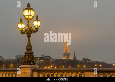 PARIS - 10. Dezember 2017: Eiffelturm bei Nacht beleuchtung und Strassenlaternen auf Alexander der dritten Brücke in Paris, Frankreich. Alexander die dritte Brid Stockfoto