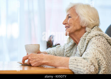 Ältere Frau mit Tasse duftenden Kaffee Stockfoto