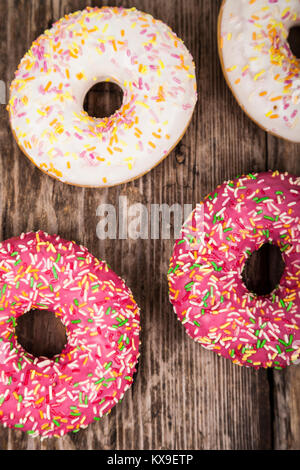 Bunte donuts Close-up auf einem hölzernen Hintergrund. Köstliches Dessert. Stockfoto