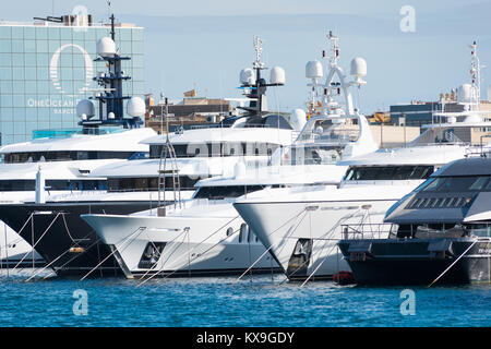 Luxus-Yachten und Cruiser vertäut im Port Vell, Barcelona, Katalonien, Spanien. Im Hintergrund ist der "One Ocean Port Vell" Mehrfamilienhaus. Stockfoto