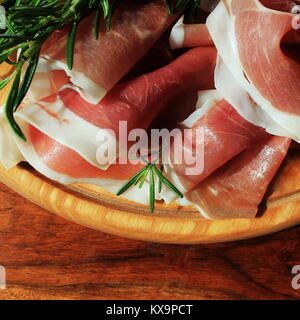 Italienische Prosciutto Crudo oder jamon mit Rosmarin auf Schneidebrett Stockfoto