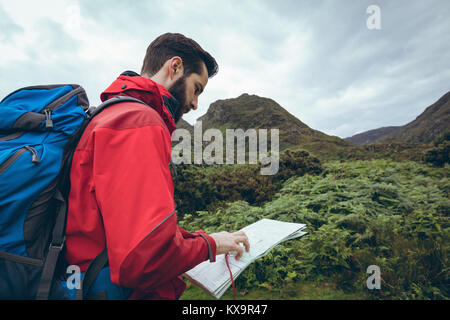 Männliche Wanderer Lesen der Karte in der Nähe der grünen Hügel Stockfoto