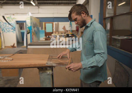 Mann Messung mit Lineal auf Surfboard Stockfoto