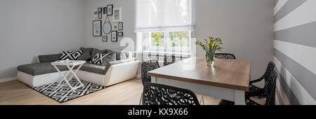 Neue Wohnung mit grauen Ecksofa, Tisch und schwarze Stühle, Panorama Stockfoto