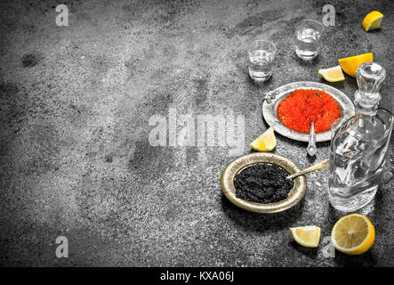Roter und schwarzer Kaviar mit Wodka. Auf rustikalen Hintergrund. Stockfoto