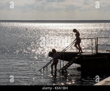 Zwei weibliche Schwimmer in Silhouette geben Sie das Wasser auf Kato Paphos, Paphos, Zypern. Stockfoto