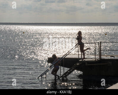 Zwei weibliche Schwimmer in Silhouette geben Sie das Wasser auf Kato Paphos, Paphos, Zypern. Stockfoto