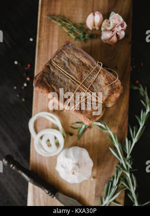 Klumpen von gesalzenem geräucherten Speck in Gaze mit einem Seil. Traditionelle russische und ukrainische Mahlzeit. Gesundes Essen mit pranami Gewürze, Kräuter, Zwiebel und Knoblauch. Stockfoto