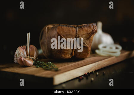 Klumpen von gesalzenem geräucherten Speck in Gaze mit einem Seil. Traditionelle russische und ukrainische Mahlzeit. Gesundes Essen mit pranami Gewürze, Kräuter, Zwiebel und Knoblauch. Stockfoto