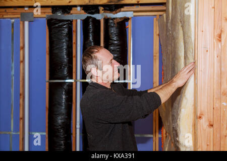 Bauarbeiter thermisch isolierend Haus Dachgeschoss mit Glaswolle, Dämmung der Haus Isolierung des Hauses Stockfoto