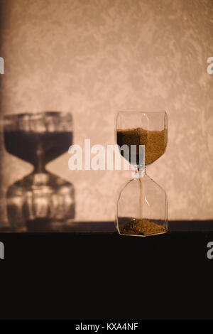 Sanduhr mit Schatten an der Wand. Zeit Konzept für die Frist, die Dringlichkeit und die Zeit läuft. Sanduhr, Eieruhr, die den letzten Minu Stockfoto