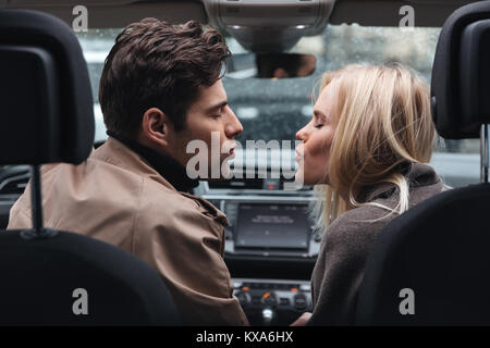 Image der jungen Liebenden Paar im Auto sitzen Küssen mit geschlossenen Augen. Stockfoto
