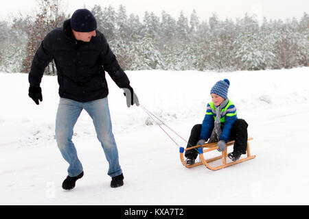 Junger Vater und Sohn Rodeln im Winter Stockfoto