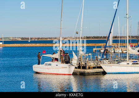 Eine Gruppe von Menschen furl die Segel eines Cuddy Cabin zwei - Segel Segelboot angedockt an Hefner Lake Marina in Oklahoma City, Oklahoma, USA. Stockfoto