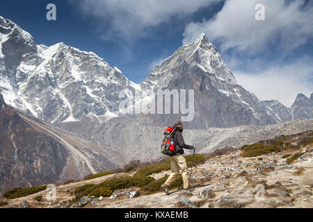 Ein Wanderer auf dem Weg zum Everest Base Camp, mit dem majestätischen Cholatse Berg im Hintergrund. Am Abend werden Sie mit köstlichen Nepalesische Küche rund um die Küche belohnt werden - Zimmer Brand bei einem Sherpa Kaffee und Unterhalten mit anderen gleichgesinnten Reisenden. Stockfoto