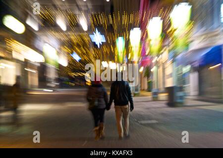 Paar geht Hand in Hand mit einem Weihnachten beleuchtete Straße, zoom Effekt, Leoben, Steiermark, Österreich. Stockfoto