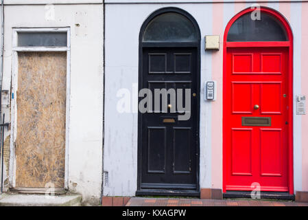 Schwarze Tür neben einer roten Tür und eine hölzerne Verkleidung Ersatz einer fehlenden Tür in der Fassade eines viktorianischen Britischen Englisch Haus Stockfoto