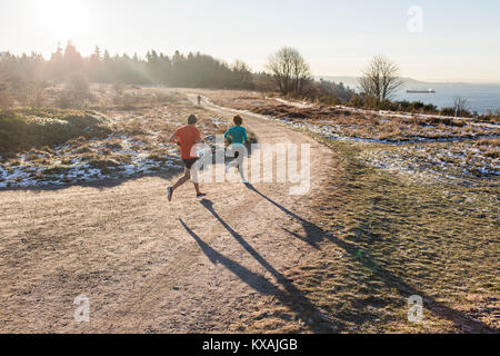 Mann und Frau joggen auf Feldweg im Winter, Discovery Park, Seattle, Washington State, USA Stockfoto