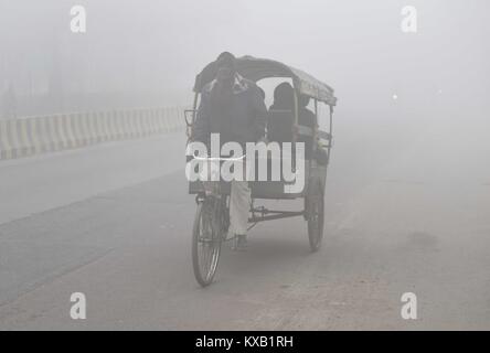 Allahabad, Uttar Pradesh, Indien. 9 Jan, 2018. Eine Rikscha Abzieher gibt seinen Passagieren eine Fahrt auf einem kalten und nebligen Morgen in Allahabad. Credit: Prabhat Kumar Verma/ZUMA Draht/Alamy leben Nachrichten Stockfoto